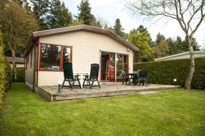 a house with a patio with chairs and a table at Camping Boslust, Bungalow de Koekoek in Putten