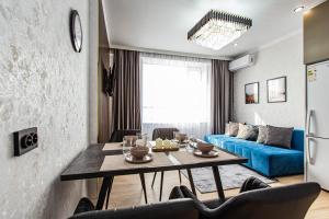 a living room with a table and a blue couch at Alpine serenity deLuxe apartment with MOUNTAIN views near the ADK shopping center and Sairan METRO station in Almaty