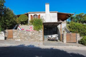 a house with a stone wall and a building at Beekeeper's house by the beach with boat & bikes. in Liyiá