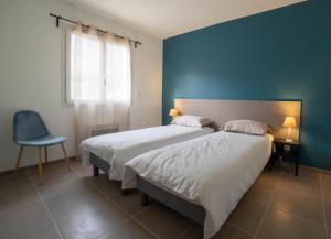 a bedroom with two beds and a blue wall at Gite 6 personnes in Vesseaux