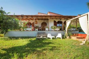 a house with two white chairs in a yard at Beekeeper's house by the beach with boat & bikes. in Liyiá