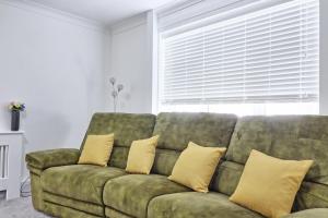uma sala de estar com um sofá verde com almofadas amarelas em The Only Way is Basildon, close to town, Trade and corporate guests also welcome em Basildon