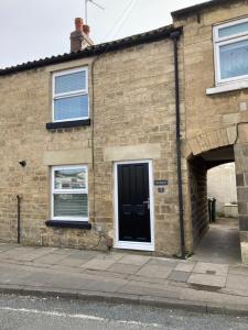 uma casa de tijolos com uma porta preta e janelas em The Burrow em Wetherby