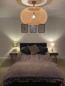 Luxury Putney Riverside Apartment في لندن: غرفة نوم بسرير كبير وثريا