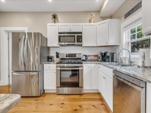 a kitchen with white cabinets and stainless steel appliances at Essex, MA Modern Historic close to Salem in Essex