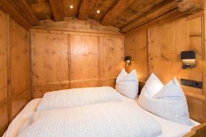 ein Schlafzimmer mit einem weißen Bett in einem Zimmer mit Holzwänden in der Unterkunft Wohnung in Reith Im Alpbachtal mit Garten und Terrasse in Reith im Alpbachtal