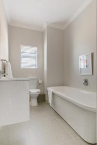 a white bathroom with a tub and a toilet at Kyalami Creek in Midrand