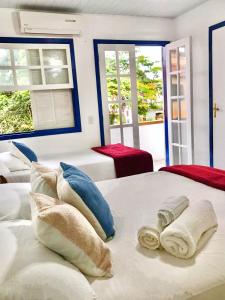 a bedroom with a large white bed with towels on it at Suites Brothers Centro in Búzios