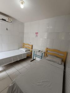 a room with two beds and a table in it at Pousada Santo Amaro in Juazeiro do Norte