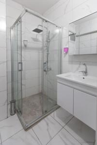 uma cabina de duche em vidro numa casa de banho branca com um lavatório em Liza Suit Hotel em Istambul