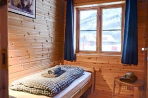 a bed in a wooden room with a window at Cabin Huskyfarm Innset in Innset