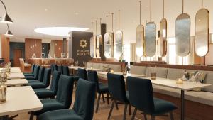 a restaurant with white tables and chairs and mirrors at Welcome Parkhotel Bochum in Bochum