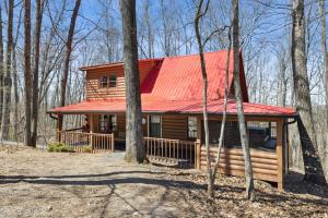 a log cabin with an orange roof in the woods at Updated family friendly Cabin, hot tub, near Gatlinburg, Pigeon Forge, Dollywood in Sevierville