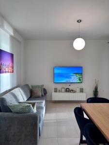 - un salon avec un canapé et une télévision murale dans l'établissement White Coast Apartment, à Saranda