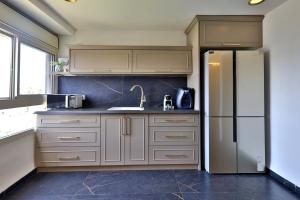 a kitchen with white cabinets and a refrigerator at שקיעה בים - דירות יוקרתיות מהממות עם ג'קוזי ונוף לים יש מקלט in Haifa +27 photos