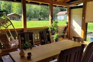 une terrasse couverte avec une table et des chaises en bois ainsi qu'une grande fenêtre. dans l'établissement Haus im Grünen, à Gosau