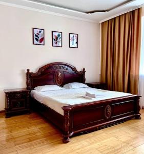 1 dormitorio con 1 cama grande de madera en una habitación en 241 Рядом с Байтереком и красивым видом на город с 3 кроватями и 2 диванами для 1-9 чел, en Astana