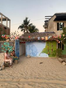 two people sitting in front of a building on the beach at Taida Hostel Rincon del Mar in Rincón