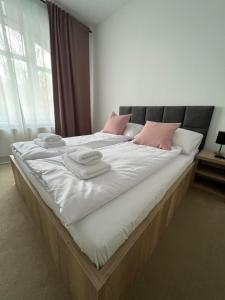 a large bed with white sheets and pink pillows at Willa Tusculum in Świeradów-Zdrój