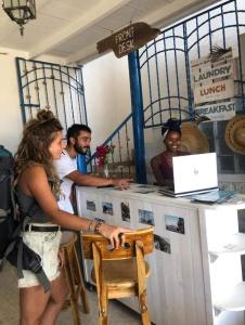 Taida Hostel Rincon del Mar في Rincón: مجموعة من الناس يقفون حول مكتب ومع الكمبيوتر المحمول