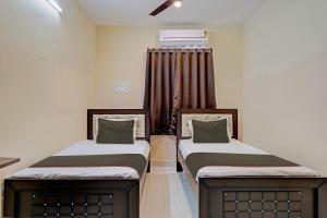 2 łóżka pojedyncze w pokoju z zasłonami w obiekcie Super OYO Flagship Rsd Grand w mieście Gunadala