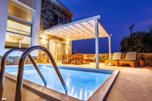 a swimming pool with a pergola next to a house at Petritis Villas in Iraklitsa