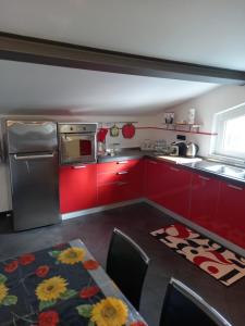 eine Küche mit roten Schränken und einem Kühlschrank aus Edelstahl in der Unterkunft CA' FRA e OLY in Castelnuovo Magra