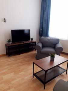 een woonkamer met een bank en een flatscreen-tv bij Hotel DH -Deutsches Haus- in Emden