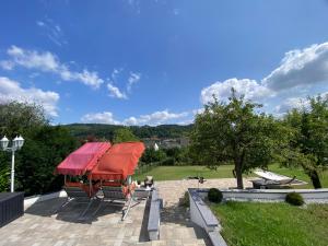 un patio con sombrilla roja, mesa y sillas en Mirabella's hidden little Paradise en Wasserliesch
