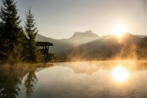 a view of a lake with the sun setting at Charmehotel Uhrerhof - Deur in Ortisei