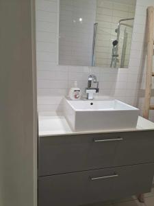 a bathroom with a white sink and a mirror at Apartment Bystranda - City Beach in Kristiansand