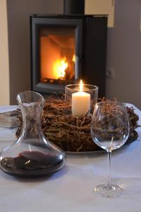 eine Kerze und zwei Gläser auf dem Tisch mit Kamin in der Unterkunft Alleinstehendes Ferienhaus in Neusüdende mit Garten in Rastede