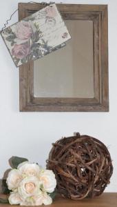ein Spiegel und ein Korb mit Blumen auf dem Tisch in der Unterkunft Alleinstehendes Ferienhaus in Neusüdende mit Garten in Rastede