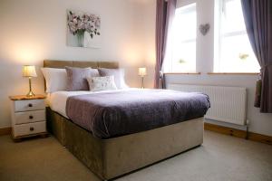 1 dormitorio con 1 cama grande y 2 ventanas en Farmleigh House,, en Donegal