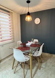 een eettafel met witte stoelen en een klok aan de muur bij CASA BONITA SALENTO - Suite para parejas o Alojamiento en Grupos in Salento