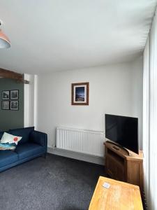 a living room with a blue couch and a flat screen tv at Cadwgan House in Rhayader