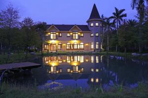 a large house with lights on a pond at night at Yun Shan Shuei Castle in Fengping