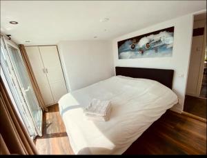 a bedroom with a white bed with a picture on the wall at Amsterdam Boathouse in Aalsmeer