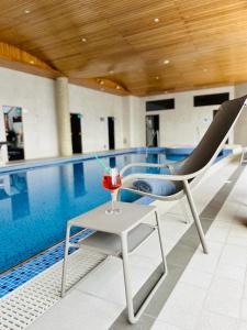 una bebida sentada en una mesa junto a una piscina en Hotel Eden, en Câmpulung Moldovenesc