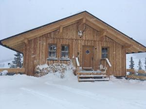 Cabaña de madera pequeña con nieve en el suelo en Jagdhütte mit Kaminofen und Sauna en Lachtal