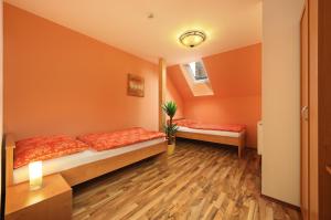 Habitación con 2 camas, paredes de color naranja y suelo de madera. en Hotel U Martina en Rožmberk nad Vltavou
