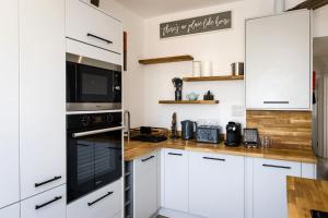 Una cocina con gabinetes blancos y electrodomésticos negros. en Horizon View - watch the waves, en Eastbourne