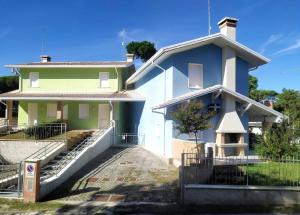 een wit en groen huis met een hek ervoor bij Ferienhaus für 5 Personen ca 60 qm in Rosolina Mare, Adriaküste Italien Venedig und Umgebung in Rosolina