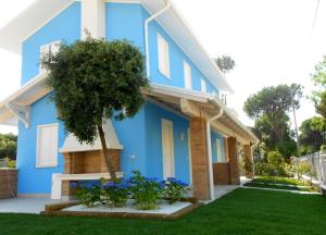 een blauw huis met een boom in de tuin bij Ferienhaus für 5 Personen ca 60 qm in Rosolina Mare, Adriaküste Italien Venedig und Umgebung in Rosolina