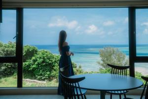 uma mulher a olhar pela janela para o oceano em Blue Steak Wonder Yomitan em Yomitan