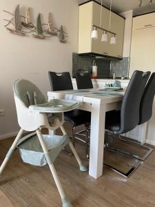 uma mesa de jantar com cadeiras e uma mesa branca e uma cozinha em "Haus Atlantic" - Wohnung "StrandGut" em Grömitz