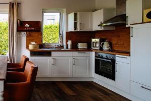 a kitchen with white cabinets and a stove top oven at Haus Willi in Butjadingen +10 photos