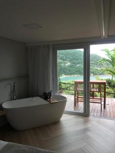 a large bath tub in a room with a balcony at Mar de Bougainville in Governador Celso Ramos
