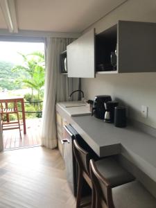 eine Küche mit einer Theke und ein paar Stühlen darin in der Unterkunft Mar de Bougainville in Governador Celso Ramos
