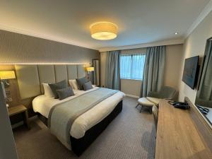 Pokój hotelowy z dużym łóżkiem i telewizorem w obiekcie Ashorne Hill Leamington Spa w mieście Leamington Spa